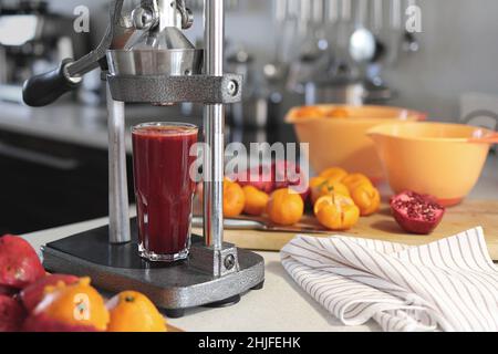 glass of freshly squeezed pomegranate juice, chopped pomegranates, tangerines and a pomegranate juicer at home. Stock Photo
