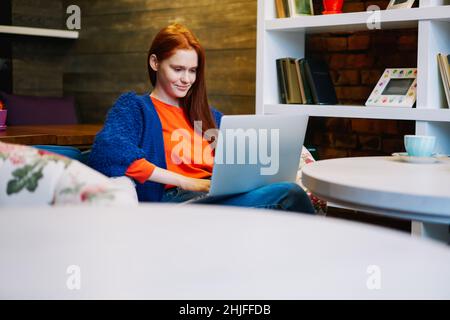 Happy female freelancer using computer in cafeteria Stock Photo