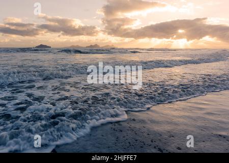 View towards Vestmannaeyjar islands off the south coast of Iceland with fast moving waves in foreground Stock Photo
