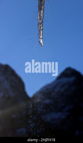 Garmisch Partenkirchen, Germany. 29th Jan, 2022. An icicle hanging from a roof thaws in the sunshine against the panorama of the Alps. Credit: Karl-Josef Hildenbrand/dpa/Alamy Live News