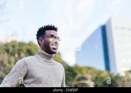 Smiling african american man in turtleneck vest looking at horizon Stock Photo