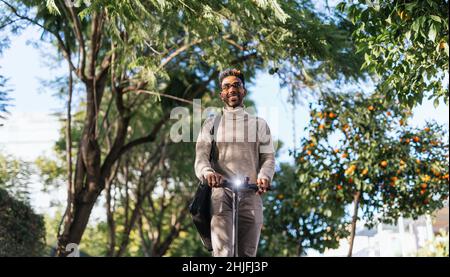 Afro-american man with turtleneck vest enjoying a ride with his electric scooter towards camera Stock Photo