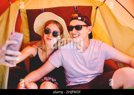 Couple of travelers taking selfie in camping tent Stock Photo