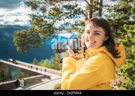 Norway. Happy Young Caucasian Woman Lady Tourist Traveler Photographer Taking Pictures Photos Near Stegastein Viewpoint In Sogn And Fjordane Fjord Stock Photo