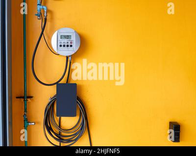Compressor digital inflator kit with rubber pipe hanging on yellow wall in car service station Stock Photo
