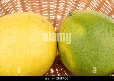 Two juicy sweet pomelos with basket, macro. Stock Photo