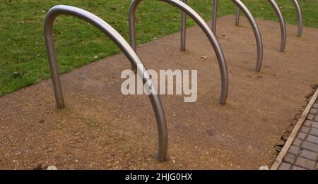 Metal cycle rack or stands on hardstanding beside grass lawn Stock Photo