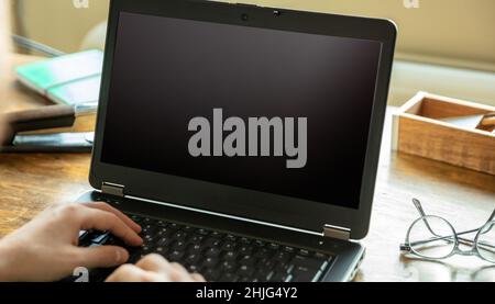 Blank laptop computer screen, Man work at home office, open notebook on wooden table, black empty display, copy space, Stock Photo