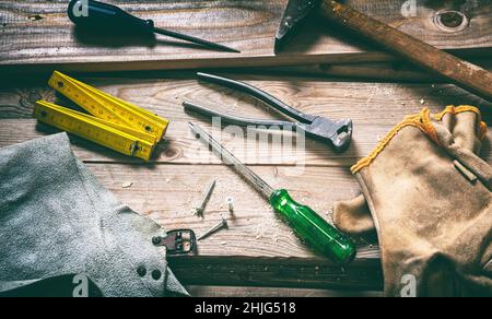 Hand tool old hammer screw driver and glove on wood, carpentry vintage equipment. Work tool used on wooden background. Construction industry Stock Photo