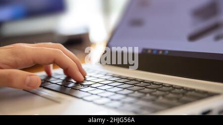 Male hand typing on laptop keyboard. Man work at home office, open notebook, close up view, selective focus. Stock Photo