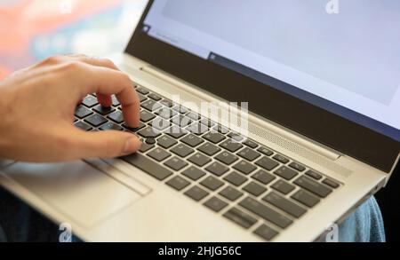 Male hand typing on laptop keyboard. Man work at home office, open notebook, close up view, selective focus. Stock Photo