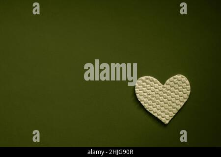 Fabric white heart on dark olive green table. Art card. Copy space Stock Photo