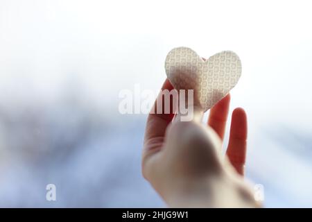 Fabric white heart in female hand on blurred blue white background Stock Photo