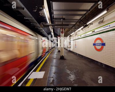 London, Greater London, England, January 5th 2022: Interior of Temple underground aka tube station as a train passes a platform with motion blur. Stock Photo