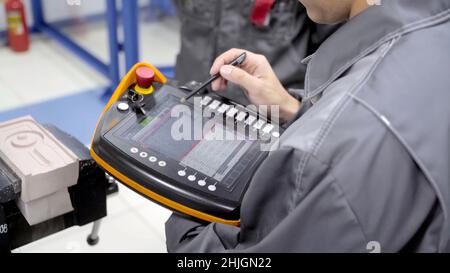 Worker uses touch control panel. Scene. Skilled worker uses electronic control panel in modern enterprise. Close-up of worker setting tasks on electro Stock Photo