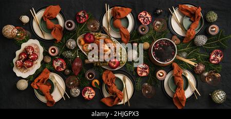 Christmas holiday dinner festive table setting with roast chicken, wine poached pears and hot spiced wine. Flat-lay of black linen table background wi Stock Photo