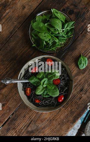 Cooked spaghetti with cuttlefish ink arranged with cheese and vegetables Stock Photo