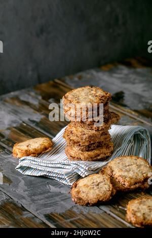 Homemade square shortbread sugar cookies with nuts and white chocolate in stack on linen kitchen towel on dark wooden table. Home sweet baking. Copy s Stock Photo