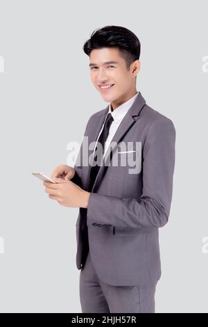 Portrait young asian business man in suit standing using smartphone to internet isolated on white background, businessman confident touch screen mobil Stock Photo
