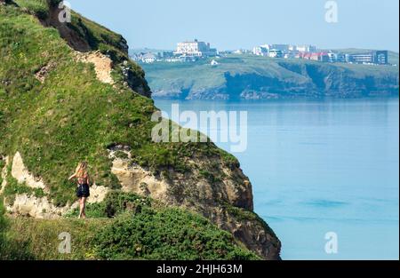 Newquay,Cornwall,England,United Kingdom-June 21st 2021: A young woman tries to get a signal on her phone while overlooking the calm bay from the cliff Stock Photo