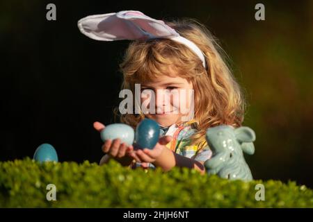Children hunting easter eggs. Excited kid boy finding easter eggs. Happy easter day. Kids with bunny ears celebrating easter. Stock Photo