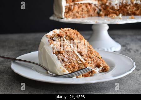 Slice of carrot cake with cream cheese frosting on a white plate with fork Stock Photo