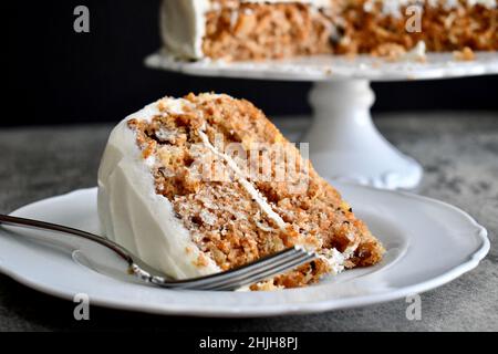Slice of carrot cake with cream cheese frosting on a white plate with fork Stock Photo