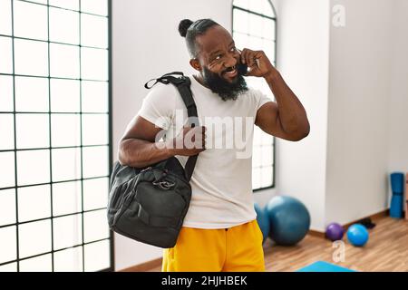 Young african american man holding gym bag talking on the smartphone at sport center Stock Photo