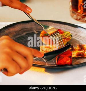 indian snack food in a plate on a table tikka,roti,naan,kebab etc, grabbing with fork and knife Stock Photo