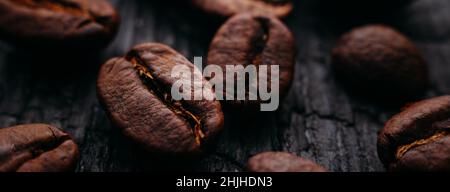 Advertising banner of coffee roasted beans close-up. Coffee on a dark background of burnt wood. Macro photography. Stock Photo