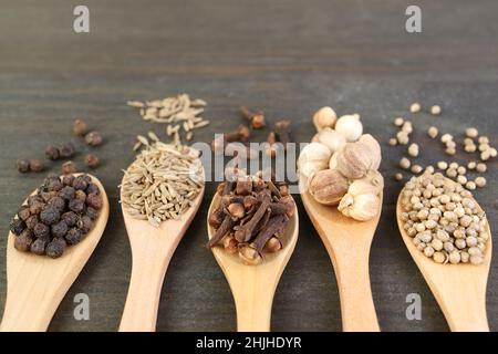 Closeup of Assortment of Spices in Wooden Spoons on Dark Brown Backdrop Stock Photo