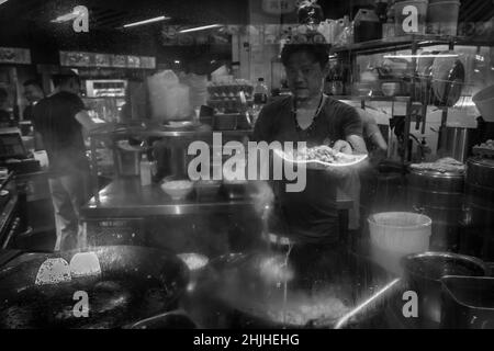 Singapore - September 07, 2019: Street hawker vendor of Chinese stall in Lau Pa Sat, Telok Ayer Market hawker center cooking food, black and white Stock Photo