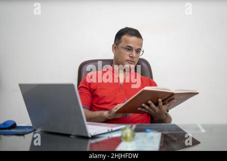 Indian man in glasses with laptop computer working at an office Stock Photo