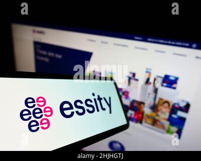 Mobile phone with logo of Swedish consumer goods company Essity AB on screen in front of business website. Focus on left of phone display. Stock Photo