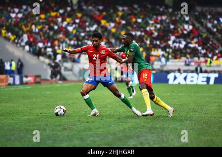 Douala, Cameroon. 29th Jan, 2022. Gambia's Saidy Janko (L) competes with Cameroon's Karl Toko Ekambi during the quarter final of the Africa Cup of Nations at the Japoma Stadium in Douala, Cameroon, Jan. 29, 2022. Cameroon won 2-0. Credit: Kepseu/Xinhua/Alamy Live News Stock Photo