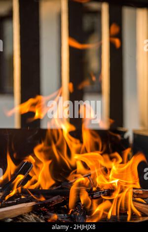 Close-up, roaring fire with blurred flames from wood logs in a stone firepit in the garden. Stock Photo