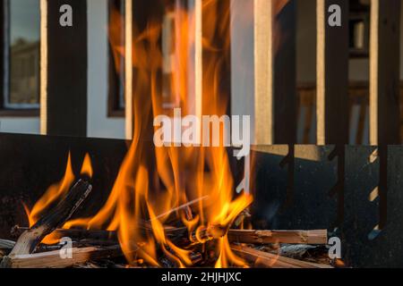 Close-up, roaring fire with blurred flames from wood logs in a stone firepit in the garden. Stock Photo
