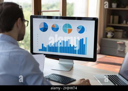 Rear view concentrated millennial businessman analyzing statistics. Stock Photo
