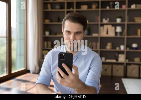 Happy confident young businessman holding mobile video call. Stock Photo