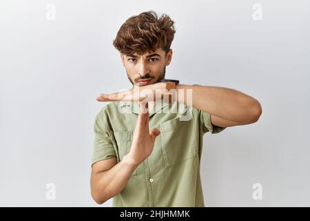 Young arab doctor man standing over isolated background doing time out gesture with hands, frustrated and serious face Stock Photo