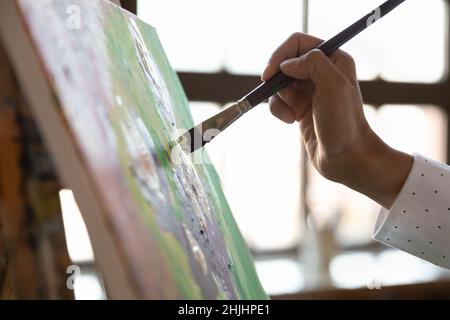 Painter hand holding paintbrush, touching canvas, putting strokes Stock Photo