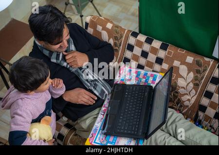 father teaching their child to study with a laptop and come and operated a laptop . Stock Photo