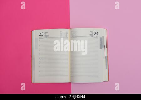 Open diary on pink table planning their time Stock Photo