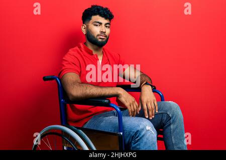Arab man with beard sitting on wheelchair looking sleepy and tired, exhausted for fatigue and hangover, lazy eyes in the morning. Stock Photo