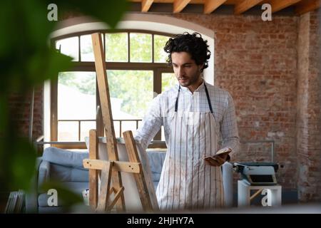 Focused busy attractive young artist student guy training painting skills Stock Photo