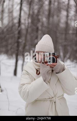 a girl with a camera on a winter walk in the woods Stock Photo