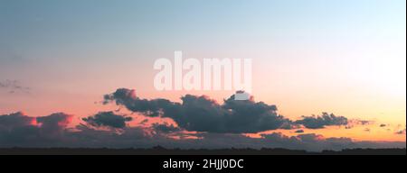 Gray clouds illuminated by the sun on a gradient sky background Stock Photo