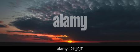 Dark sunset with gloomy clouds and red light on the horizon Stock Photo