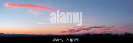 Panorama of dramatic colorful sunset with dark and bright clouds. The sun's rays are breaking through the cloudy sky. Dark clouds against a bright sat Stock Photo