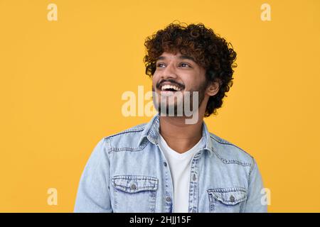 Happy smiling young indian man looking, dreaming on yellow background. Stock Photo